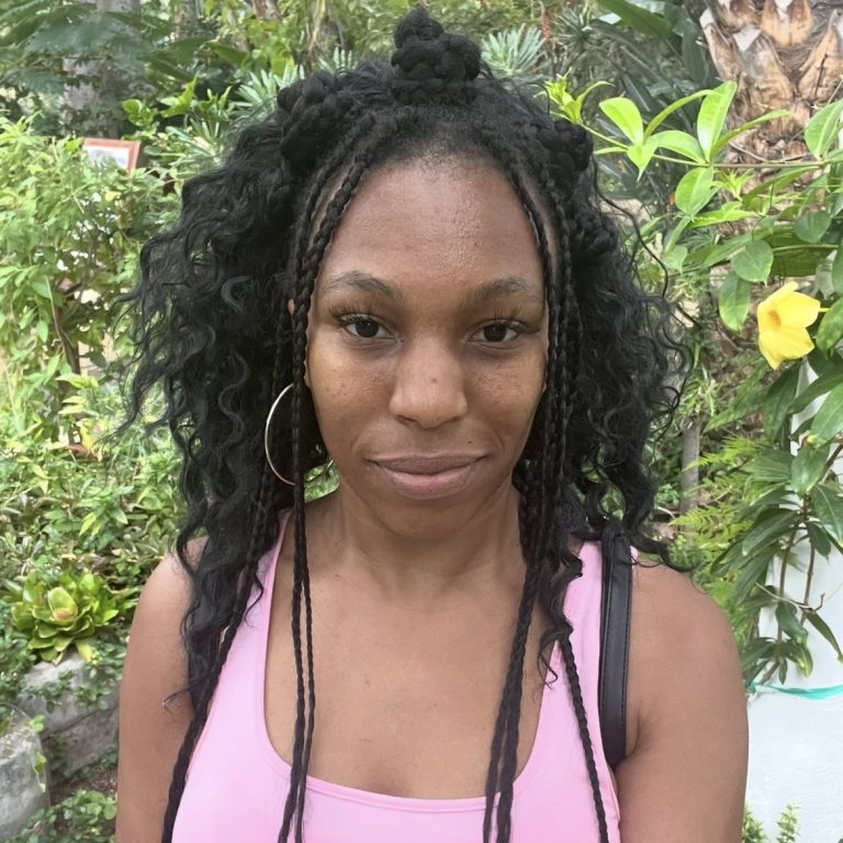 Young woman with long dark hair styled in a ponytail, wearing a black top.